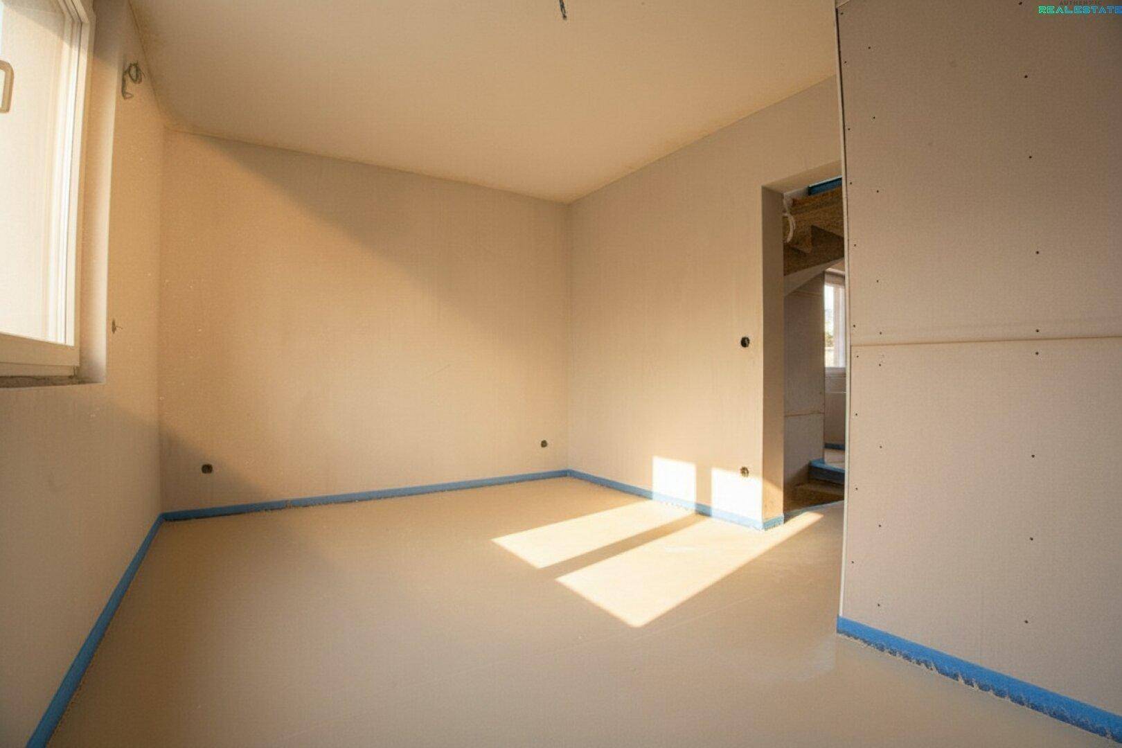 Schlafzimmer im Rohbau mit Fenster und viel Tageslicht.