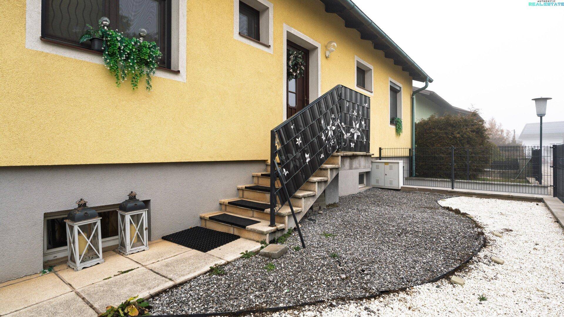 Eingangsbereich des Hauses mit dekorativer Treppe und Kiesbeet.