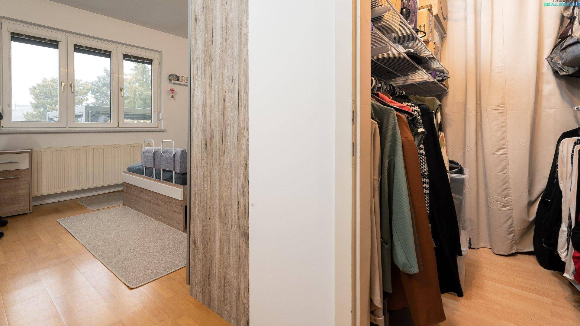 Schlafzimmer mit begehbarem Kleiderschrank und Holzboden.