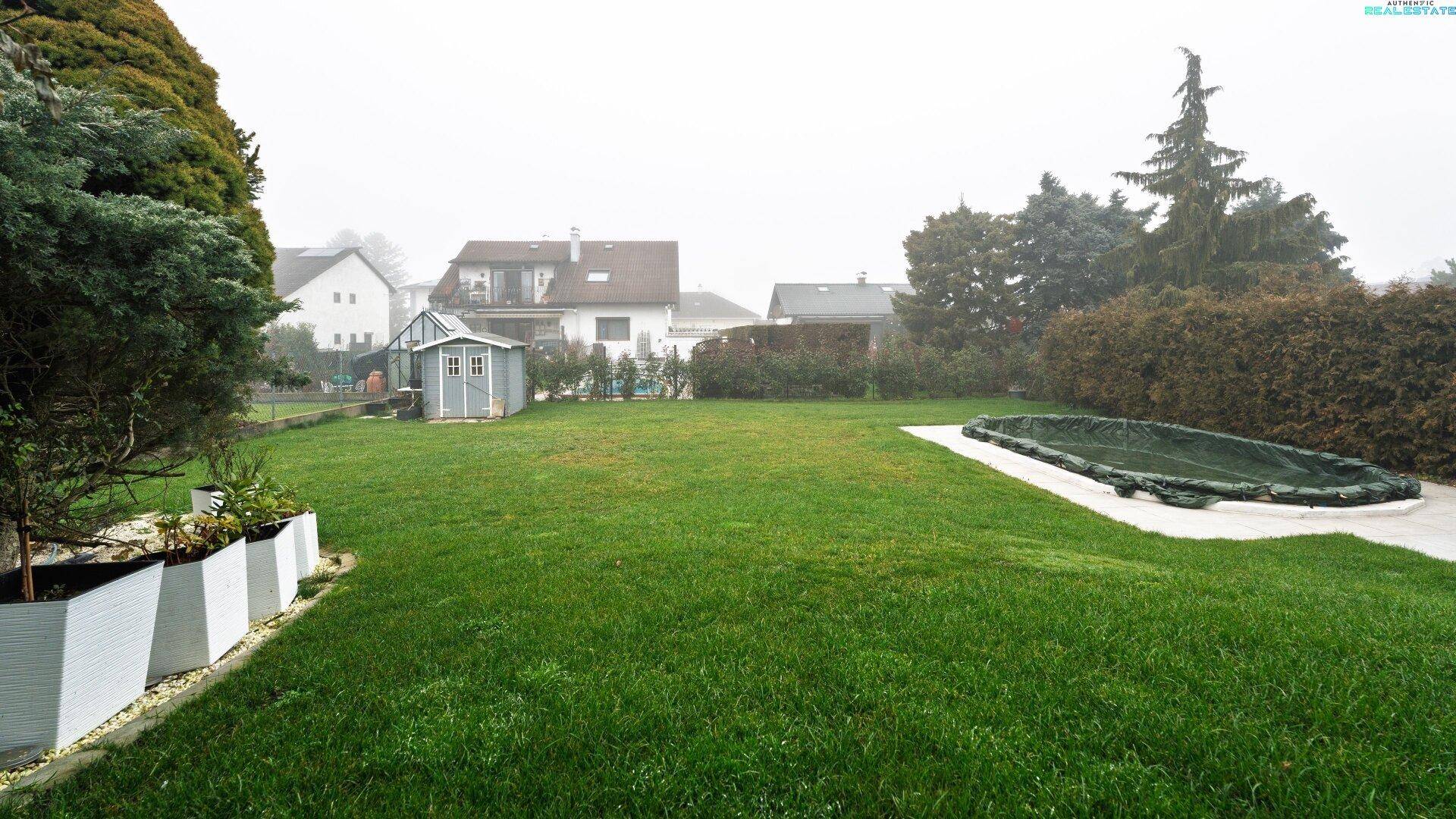 Weitläufiger Garten mit großer Rasenfläche, Pool und Gartenhaus im Hintergrund.