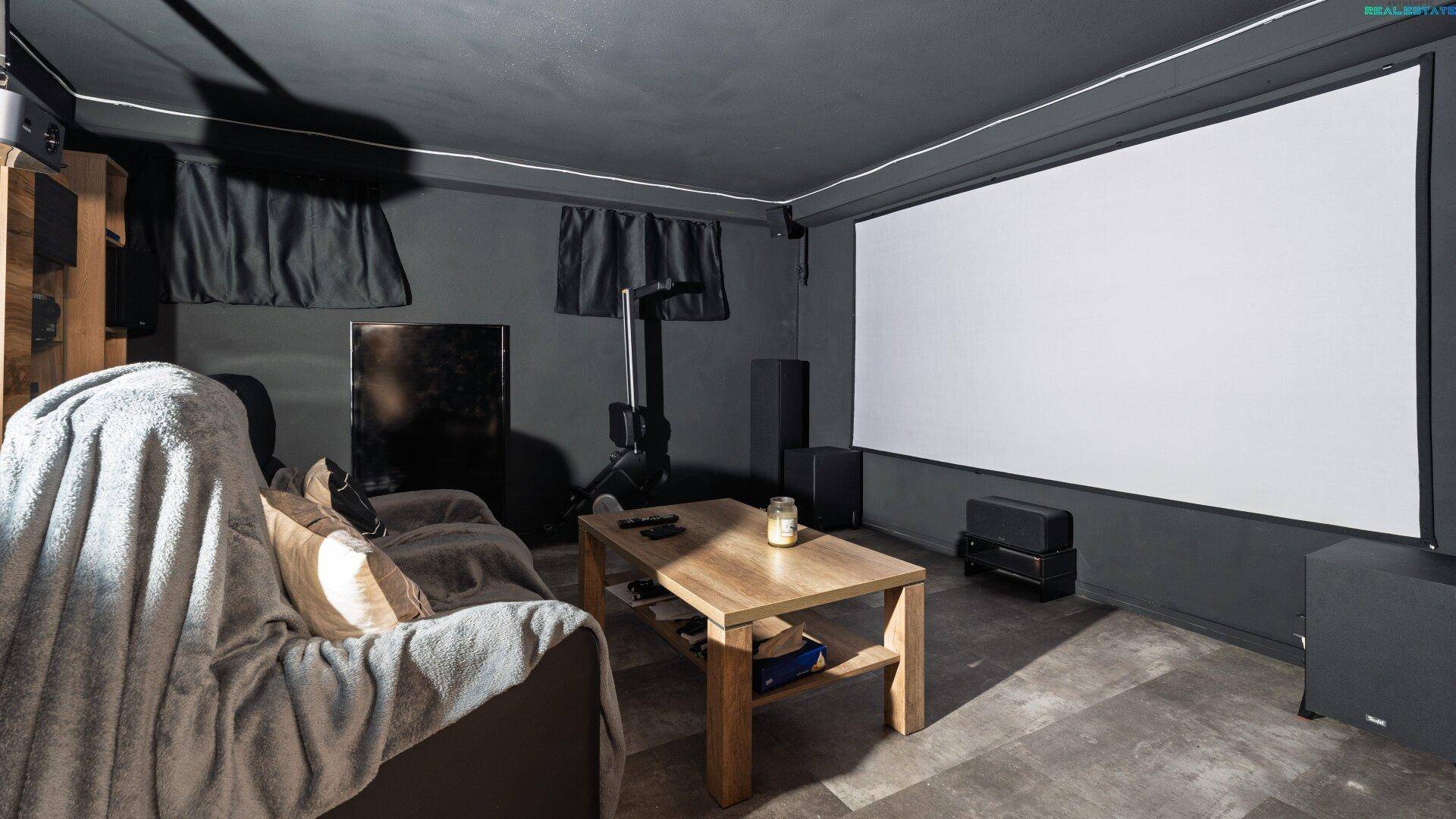 Dunkler Medienraum im Keller mit großer Leinwand und bequemer Couch.