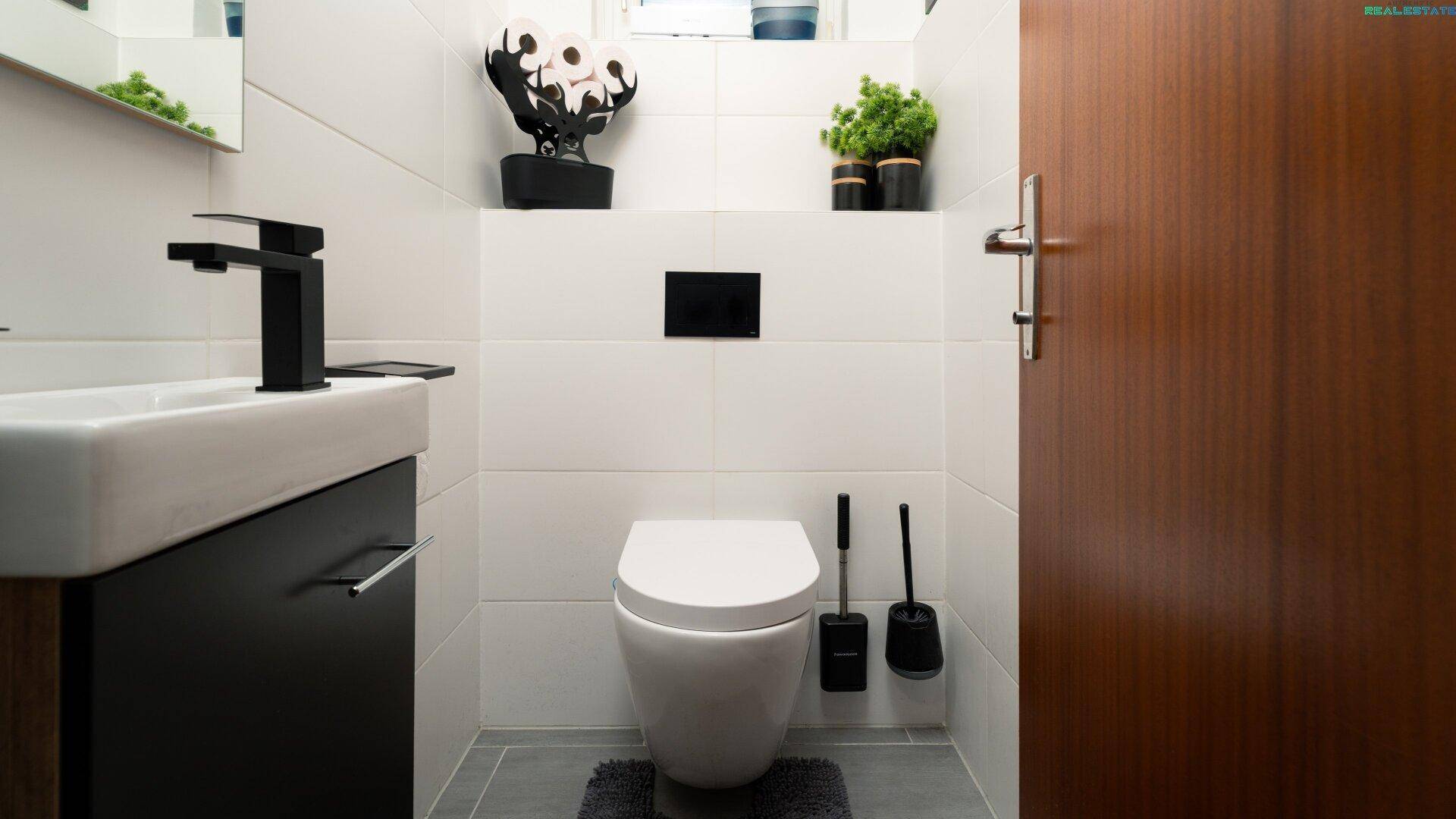 Modernes Gäste-WC mit wandhängender Toilette und stilvollem Waschbecken.