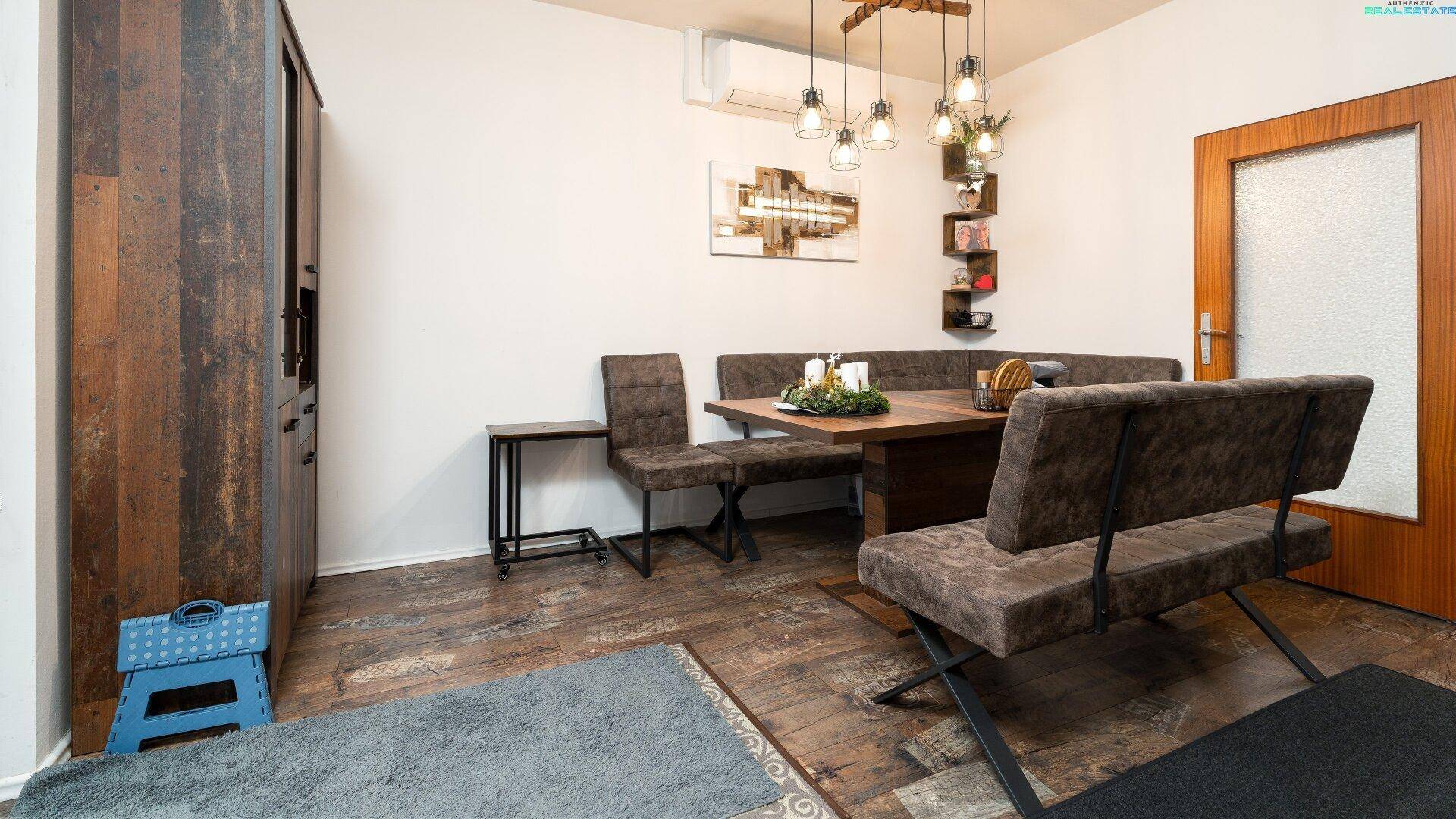 Essbereich im offenen Wohnraum mit Holztisch und Sitzbank.