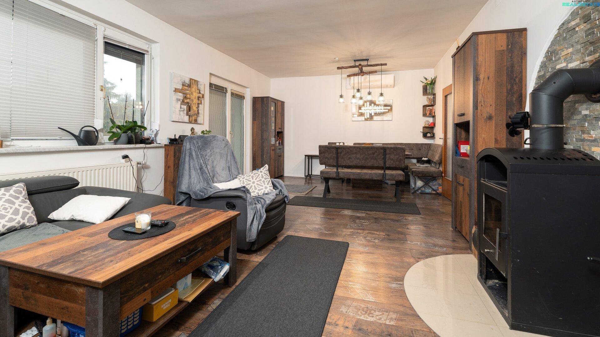 Gemütliches Wohnzimmer mit Holzboden, Kaminofen und bequemer Sitzecke.