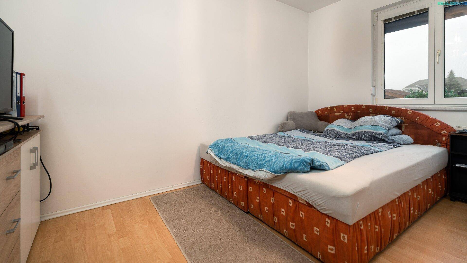 Weiteres Schlafzimmer mit Bett, Fernseher und Holzboden.