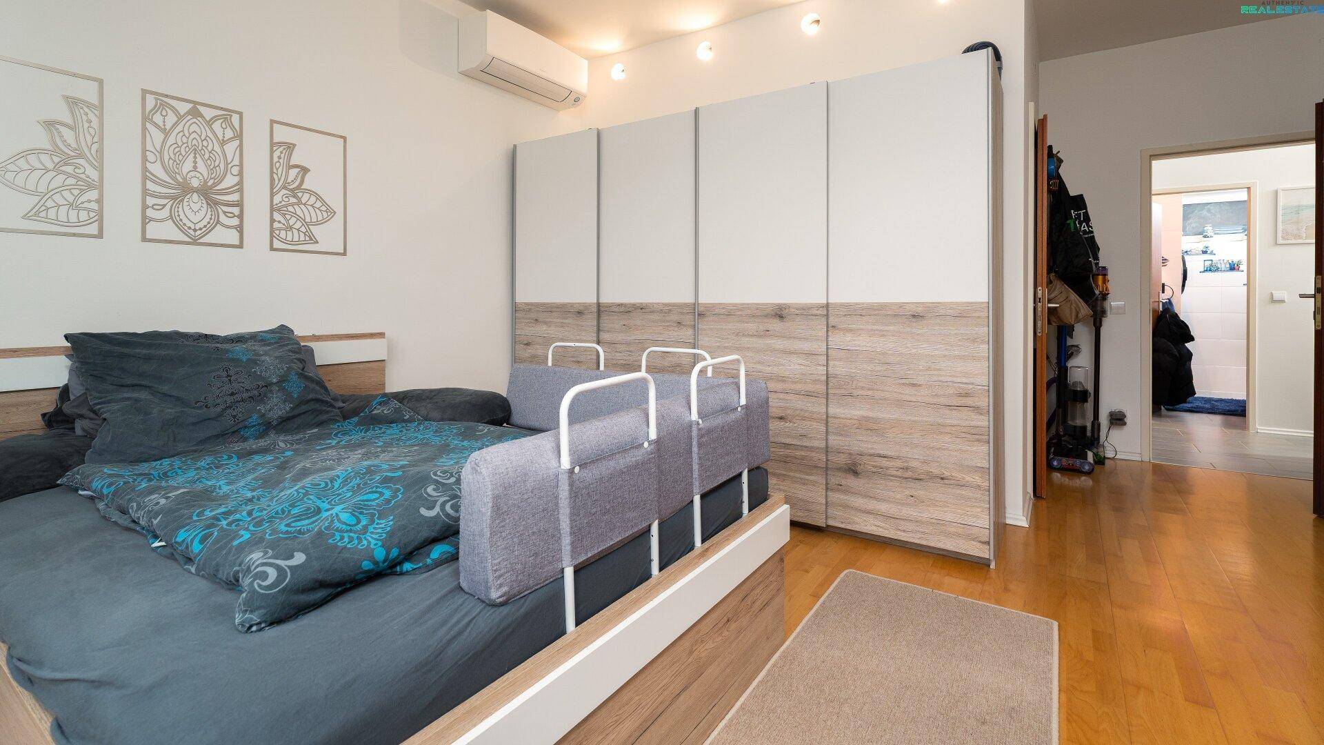 Schlafzimmer mit Einbauschränken, Holzboden und Klimaanlage.