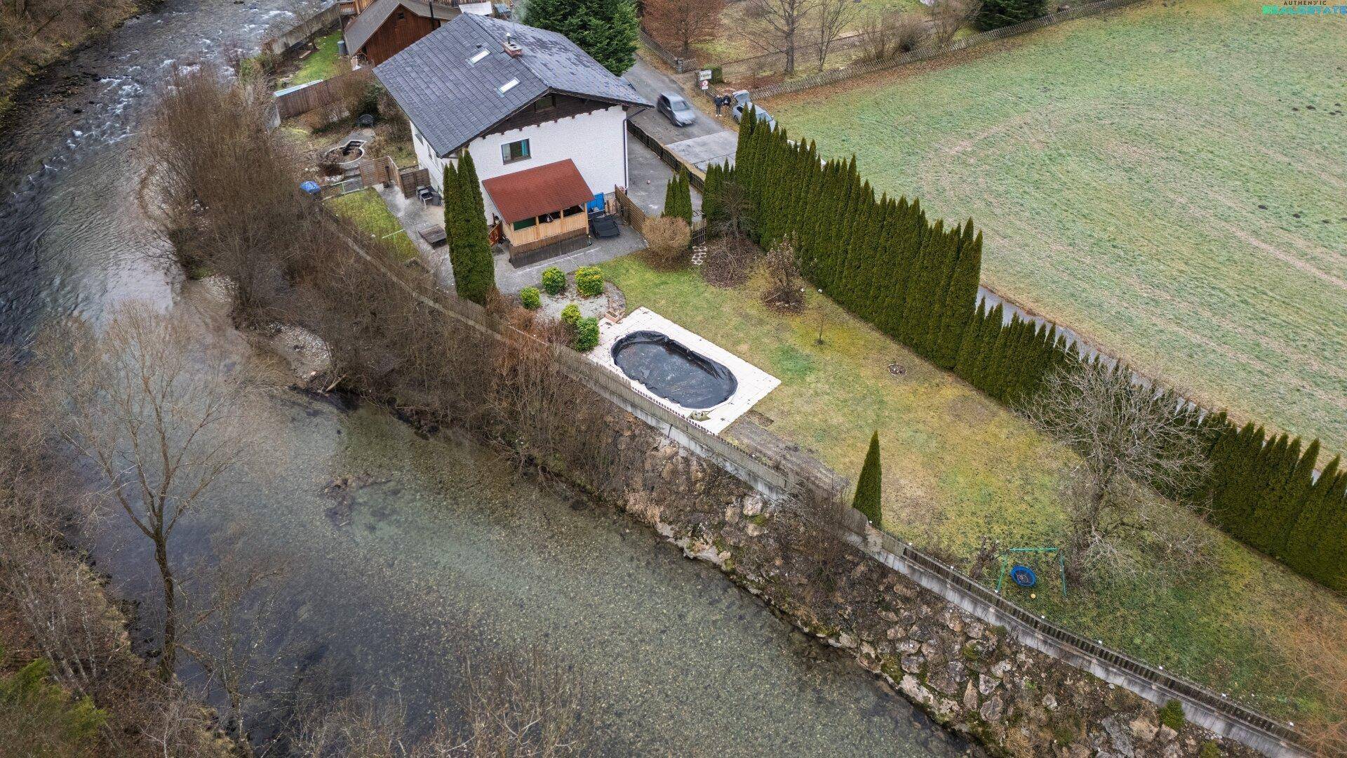 Luftaufnahme des Hauses mit Garten, Pool und angrenzendem Fluss in ländlicher Umgebung.