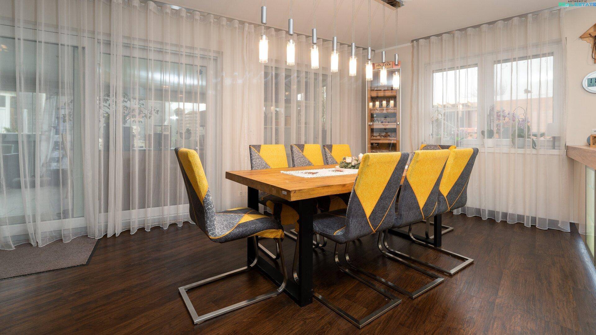 Heller Essbereich mit großem Holztisch, modernen Stühlen und Zugang zur Terrasse.