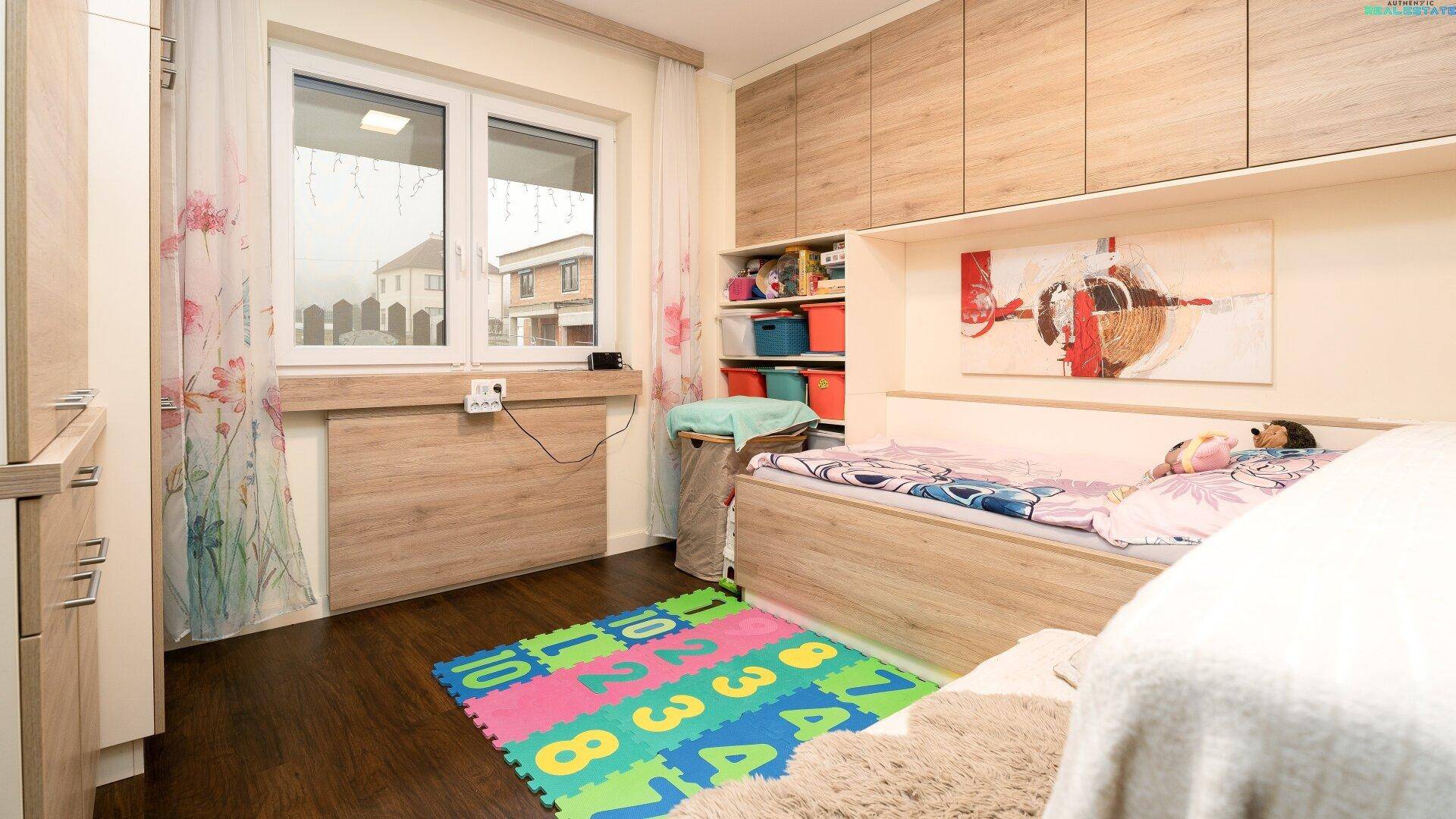 Helles Kinderzimmer mit Holzboden, Einbauschränken und großem Fenster.