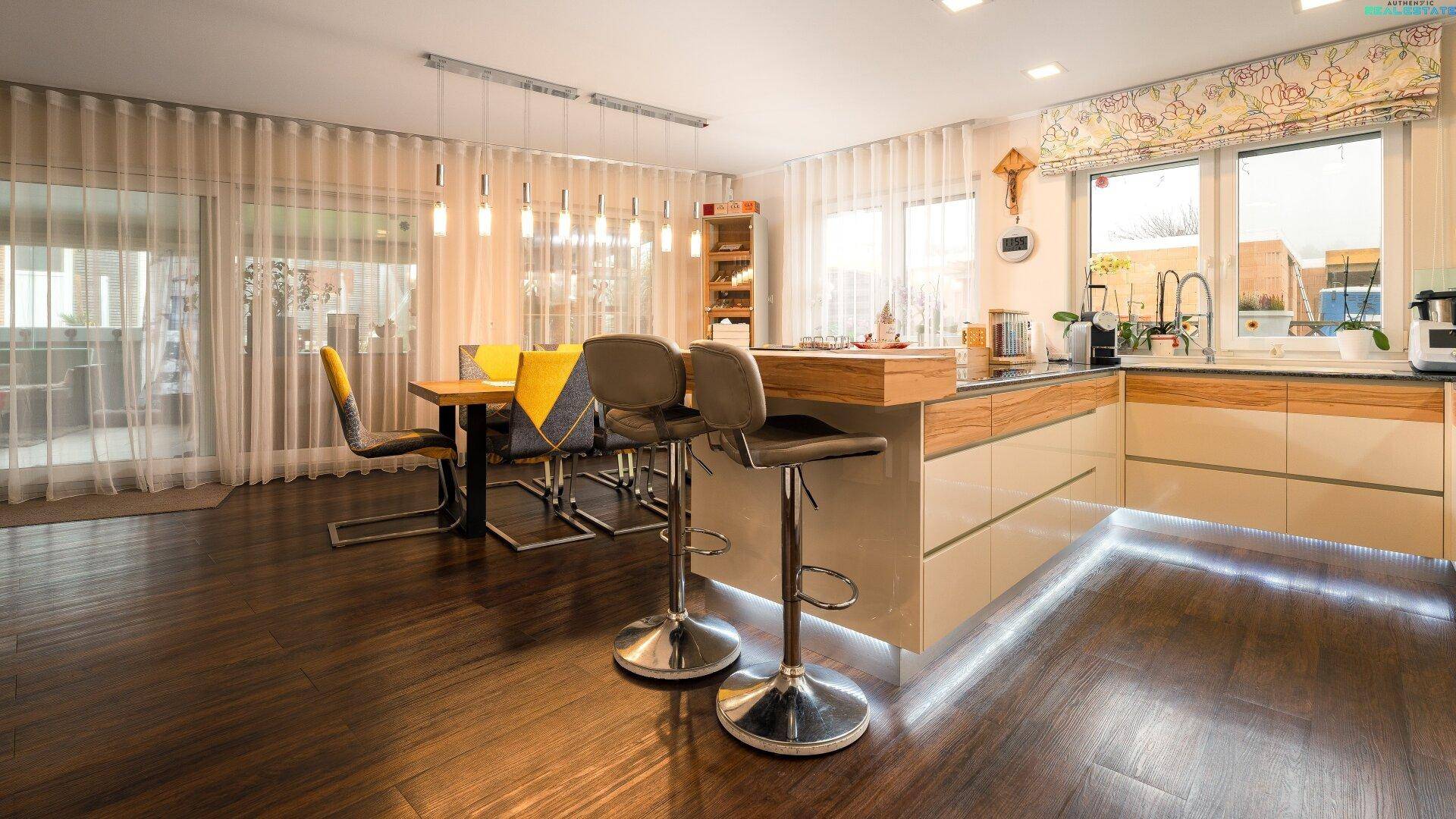 Offener Wohn-Essbereich mit moderner Küche, Esstisch und Barhockern, lichtdurchflutet.