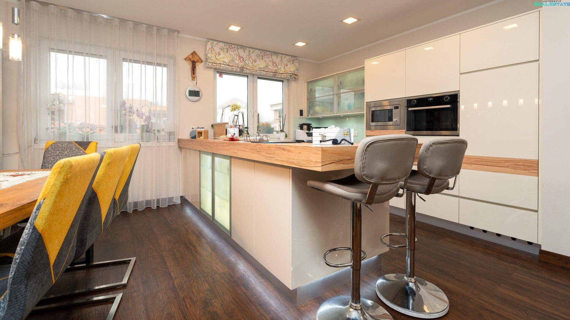 Moderner offener Küchenbereich mit Kochinsel, Barhockern und angrenzendem Essbereich.