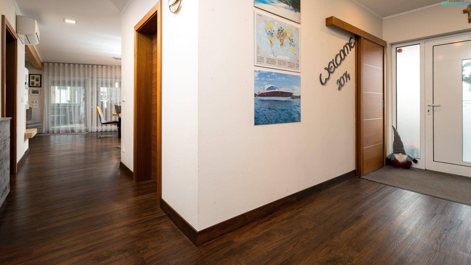 Heller Flur mit dunklem Holzboden, Holztüren und Zugang zu weiteren Räumen.