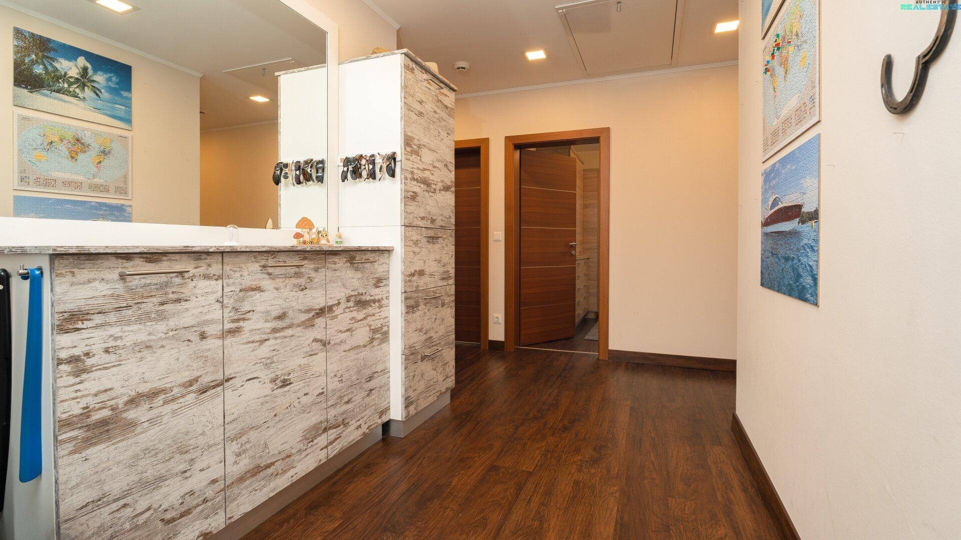 Eingangsbereich mit dunklem Holzboden, einer Kommode und dekorativen Elementen an der Wand.