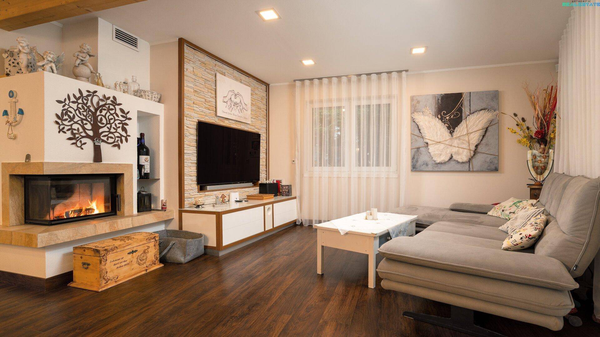 Gemütliches Wohnzimmer mit Kamin, großem Sofa und dunklem Holzboden, modern eingerichtet.