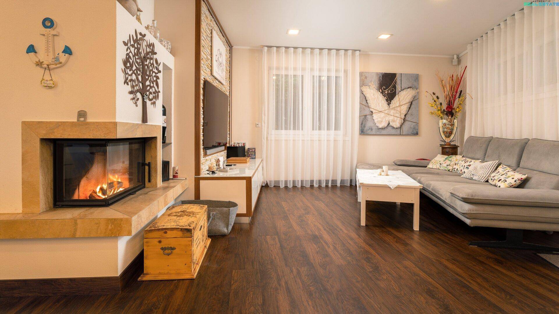 Helles Wohnzimmer mit Kamin, bequemer Couch und dunklem Holzboden, einladend gestaltet.