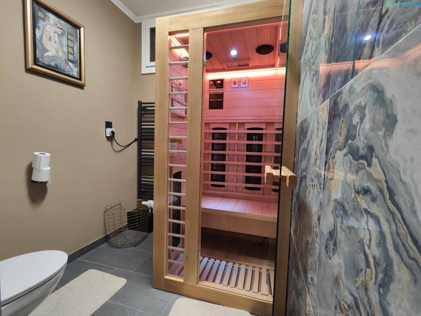 Modernes Badezimmer mit integrierter Infrarotsauna, Wand-WC und stilvollen Fliesen.