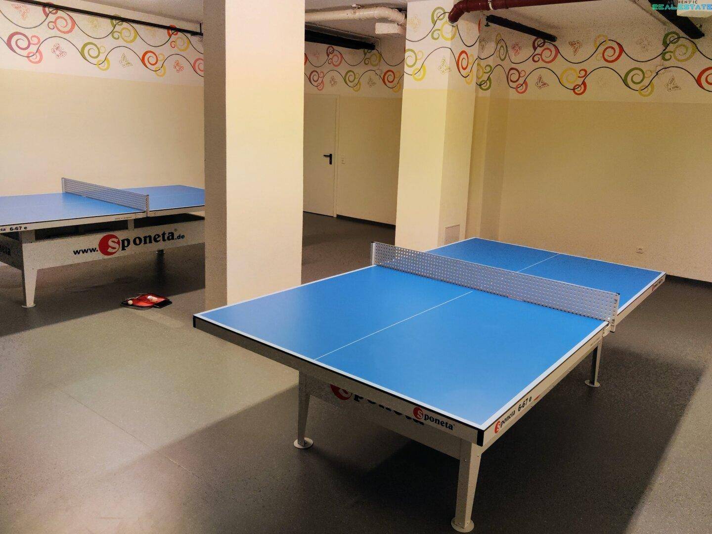 Geräumiger Raum mit zwei Tischtennisplatten, ideal für sportliche Aktivitäten und Unterhaltung.