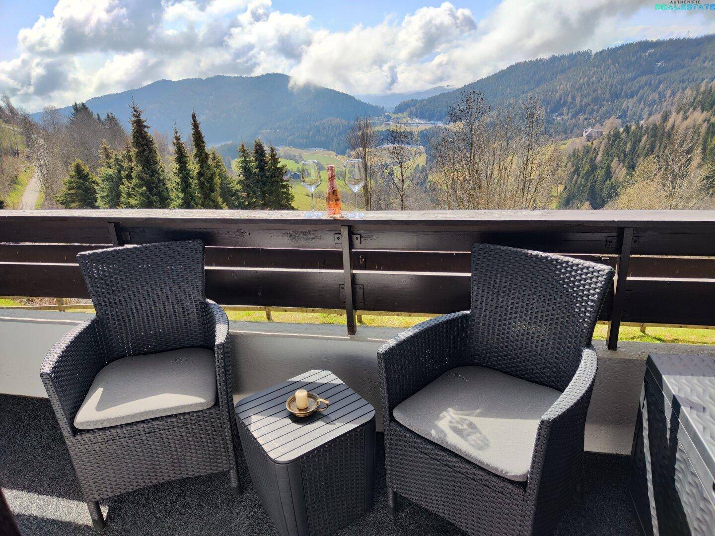 Gemütlicher Balkon mit Sitzgelegenheiten und einem weiten Blick auf die umliegende Berglandschaft.
