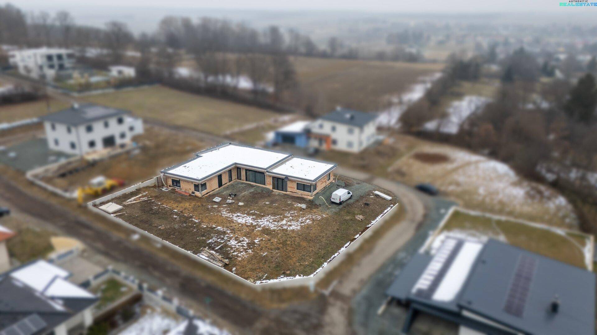Luftaufnahme eines modernen Einfamilienhauses in ländlicher Umgebung mit umliegenden Grundstücken.