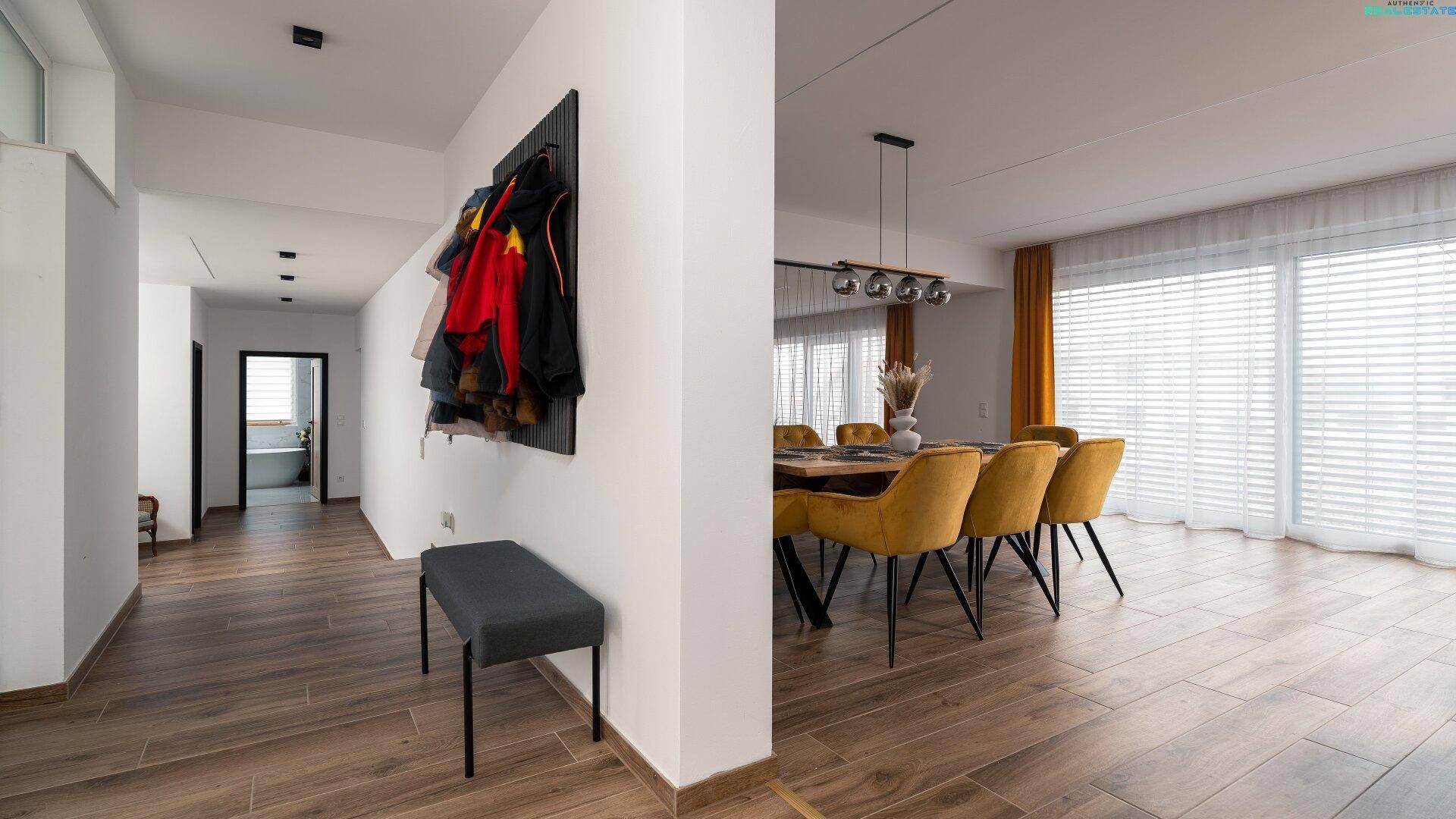 Heller Flur mit Holzboden, Garderobe und offenem Blick in den Essbereich, einladend und funktional.