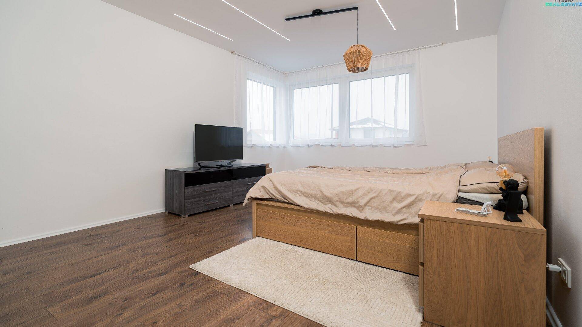 Schlafzimmer mit Holzbett, Nachttischen und großem Fenster für viel Tageslicht und eine angenehme Atmosphäre.