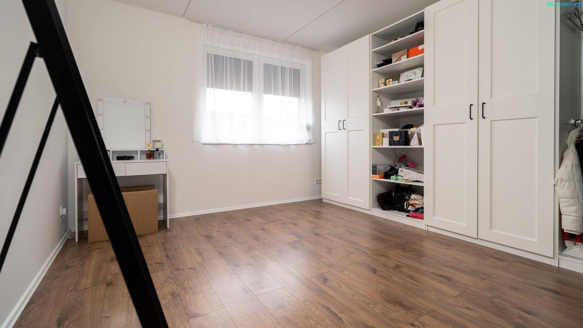 Geräumiges Zimmer mit Einbauschränken, Holzboden und großem Fenster, vielseitig nutzbar.
