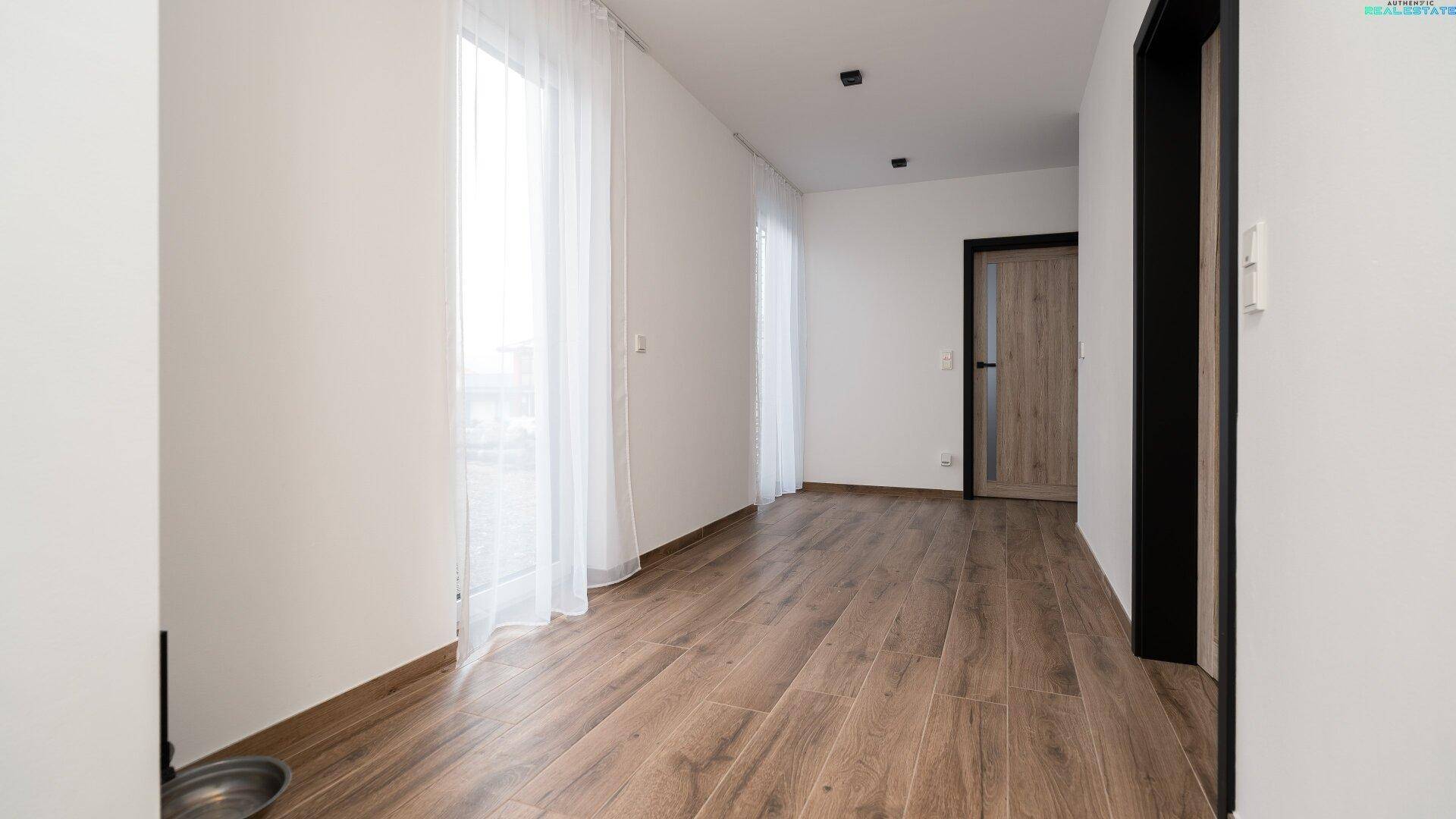 Langer, heller Flur mit Holzboden und Fenstern, die für natürliche Beleuchtung sorgen, verbindet die Räume.