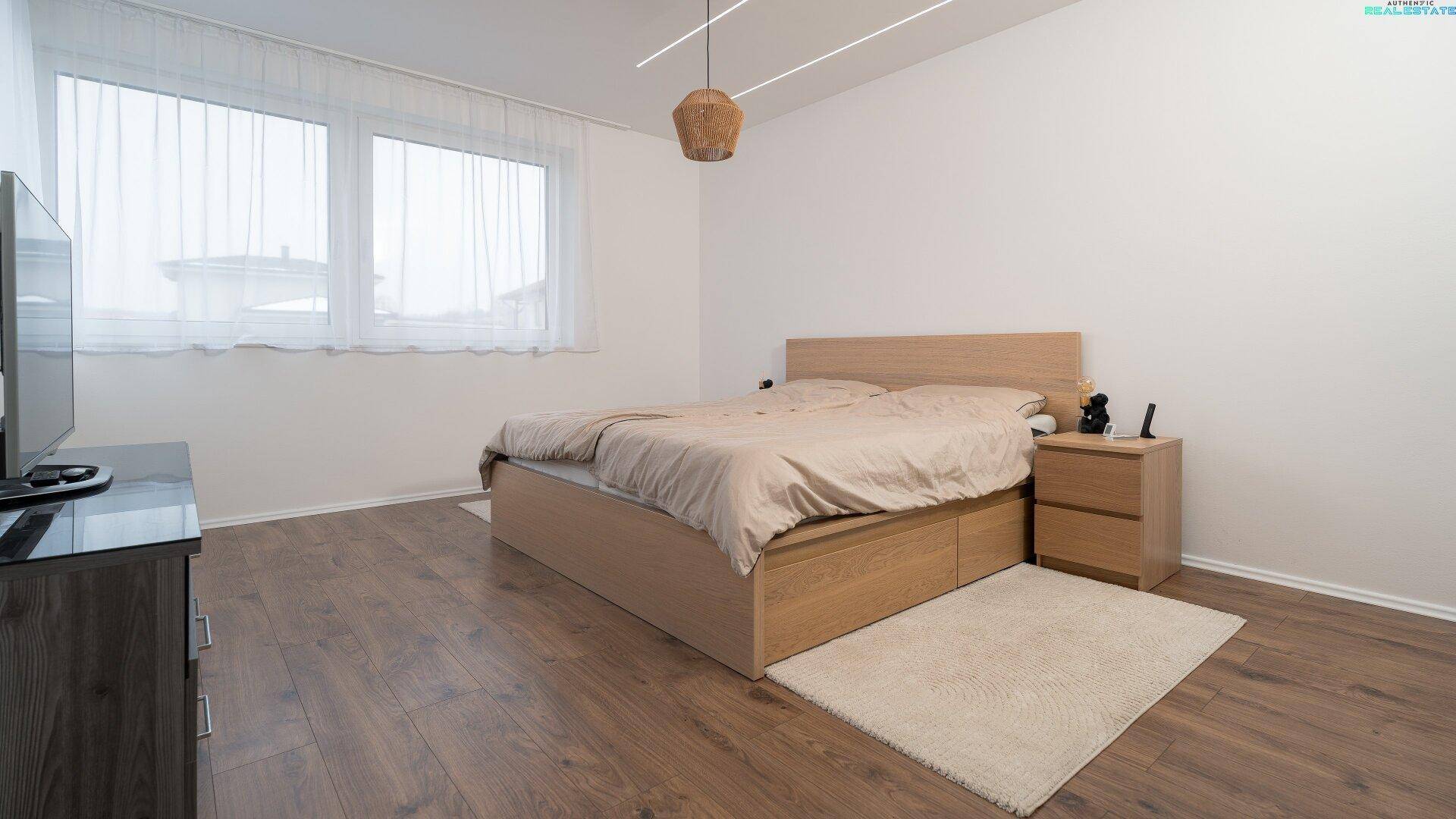 Helles Schlafzimmer mit Holzbett, Nachttischen und großem Fenster, das eine ruhige Schlafumgebung schafft.