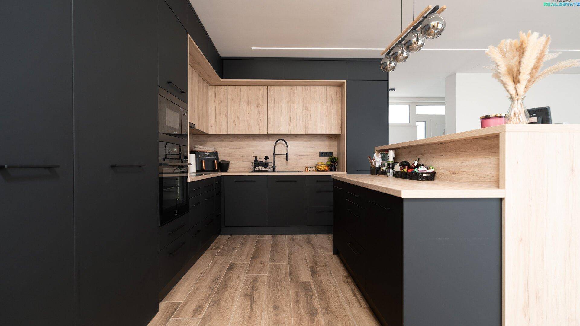 Elegante Küche mit schwarzen und holzfarbenen Schränken, integrierten Geräten und modernem Design.