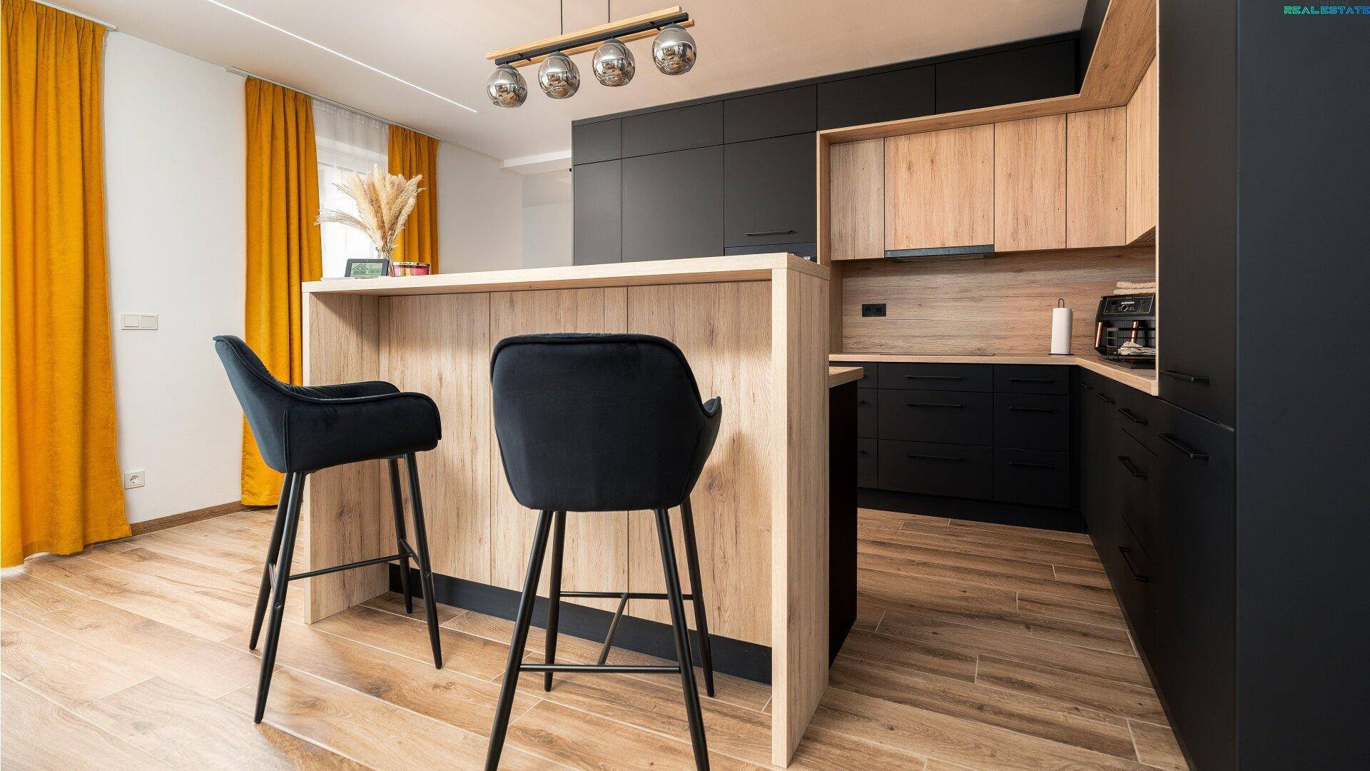 Moderne Küche mit Frühstücksbar, schwarzen Barhockern und Holzboden, perfekt für schnelle Mahlzeiten.