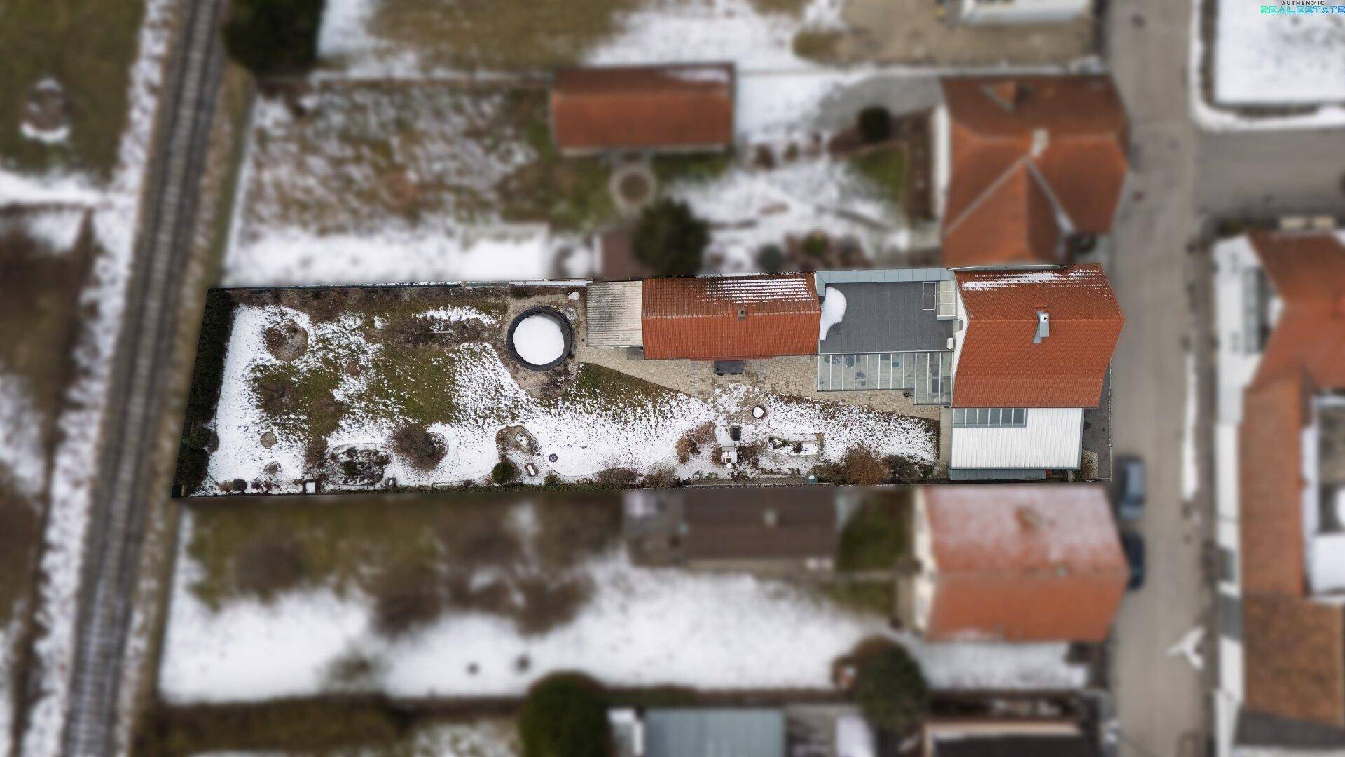 Luftaufnahme des Hauses mit großem Garten, Terrasse und umliegender Bebauung.