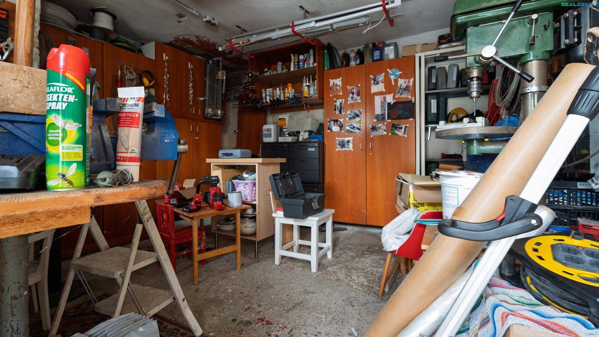 Werkstatt oder Abstellraum mit vielen Regalen, Werkzeugen und Arbeitsflächen.