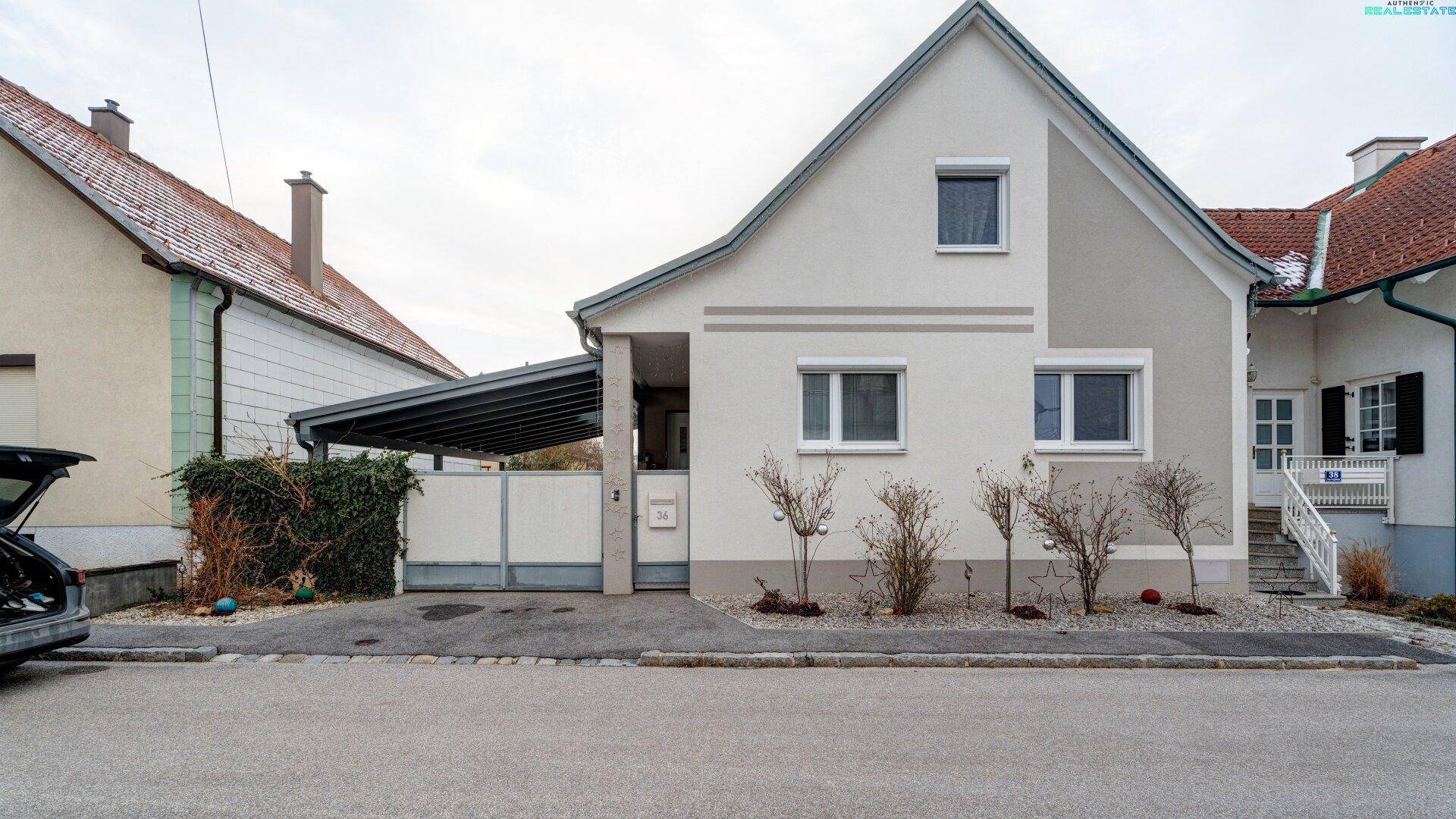 Einfamilienhaus mit Carport und gepflegter Fassade in ruhiger Wohngegend.