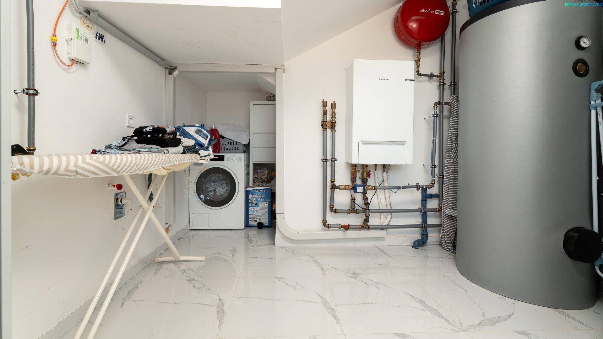 Hauswirtschaftsraum mit Heizungsanlage, Waschmaschine und Bügelbrett.