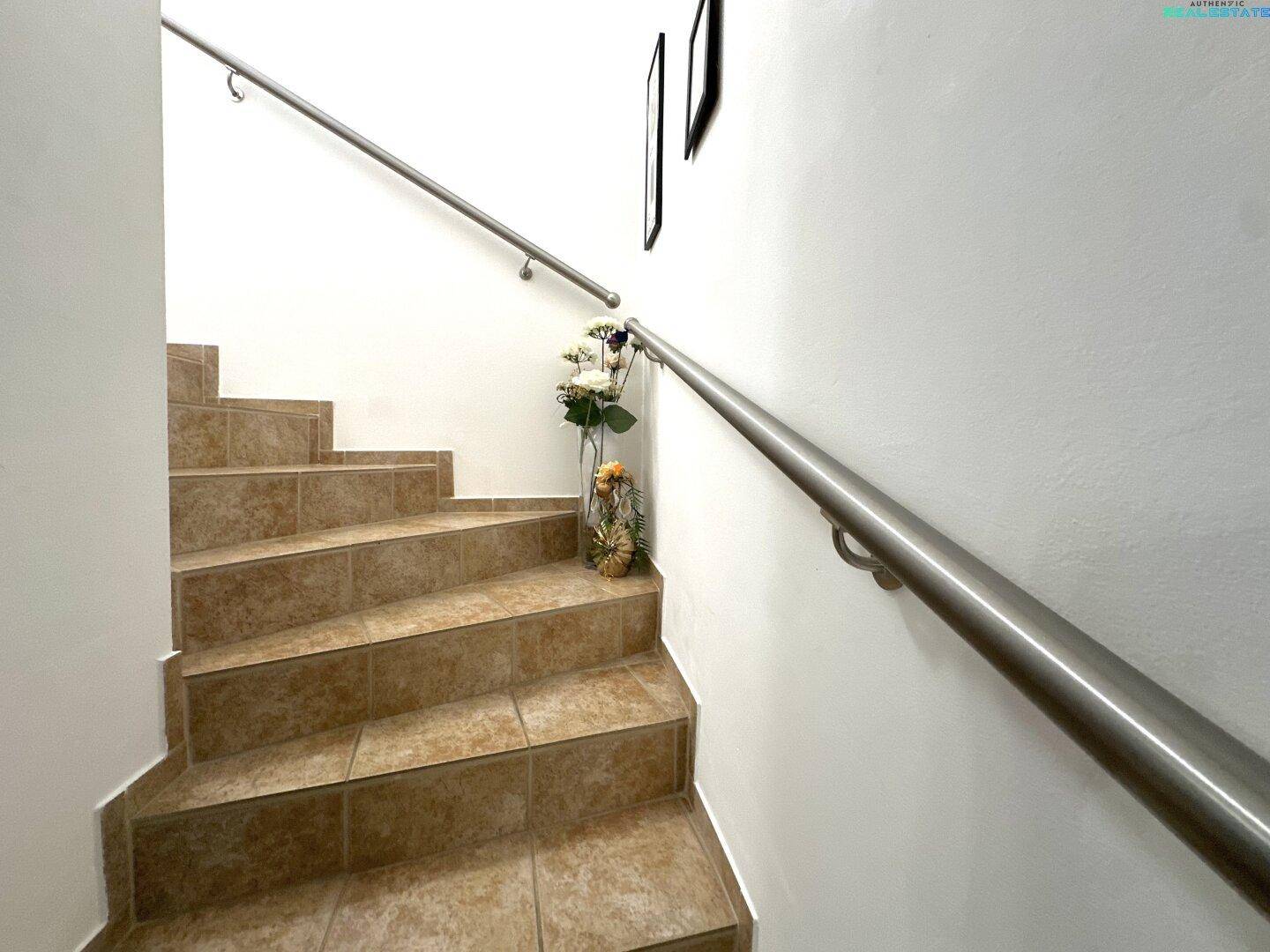 Geflieste Treppe mit modernem Edelstahlgeländer, die die verschiedenen Etagen des Hauses verbindet.