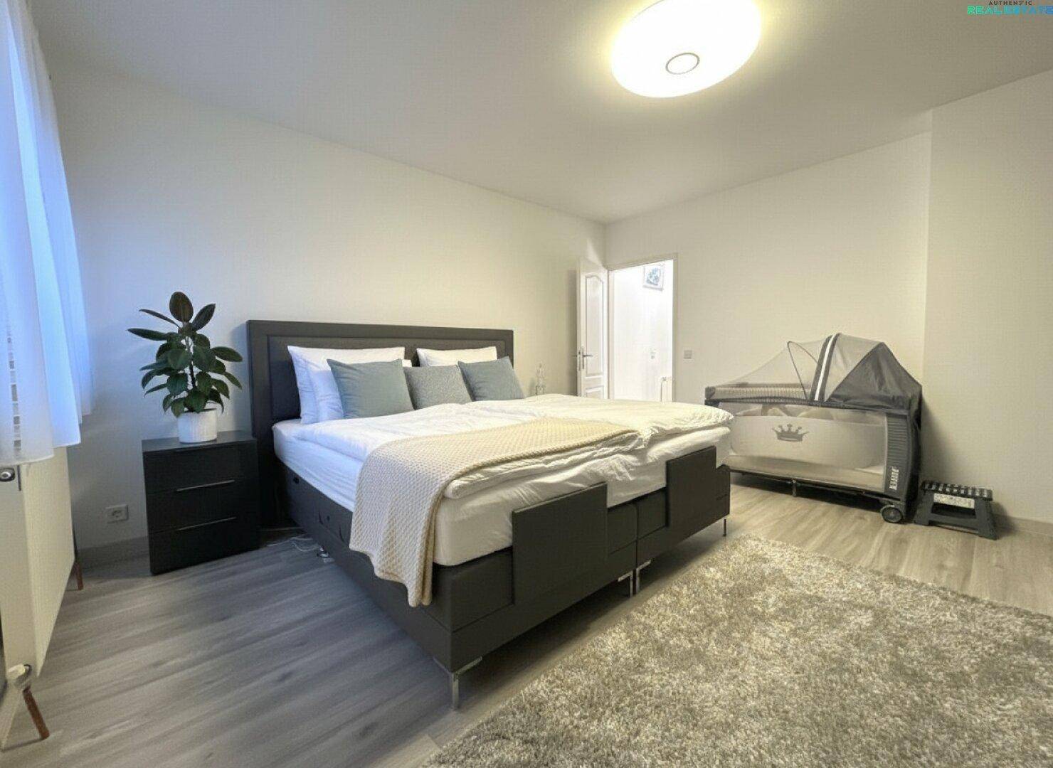 Helles Schlafzimmer mit Doppelbett, Nachttischen und einem Kinderbett, ideal für Familien.