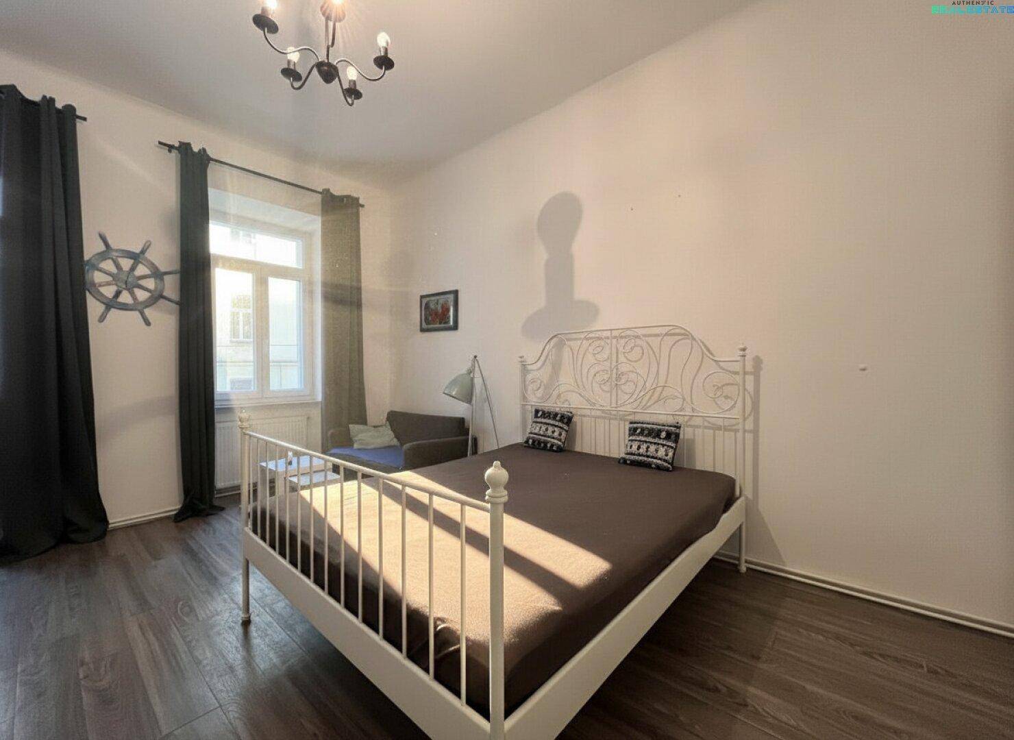 Helles Schlafzimmer mit Laminatboden, großem Fenster und dekorativem Steuerrad an der Wand.