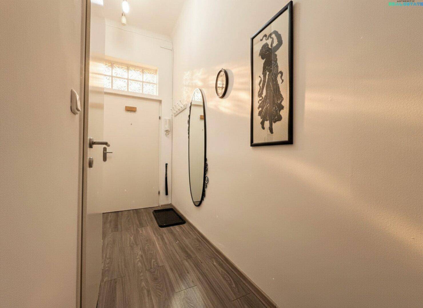 Heller Flur mit Laminatboden, großem Spiegel und dekorativem Kunstwerk an der Wand.