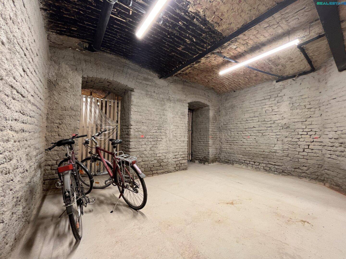 Geräumiger Fahrradraum im Keller mit unverputzten Ziegelwänden und ausreichend Platz.
