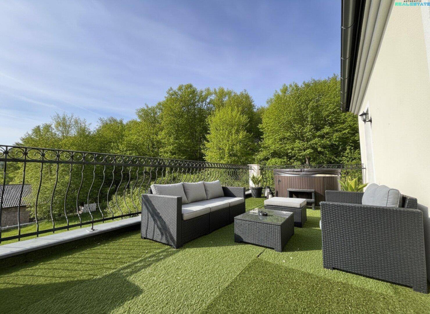 Großer Balkon mit Kunstrasen, Lounge-Möbeln und Whirlpool mit weitem Blick ins Grüne.