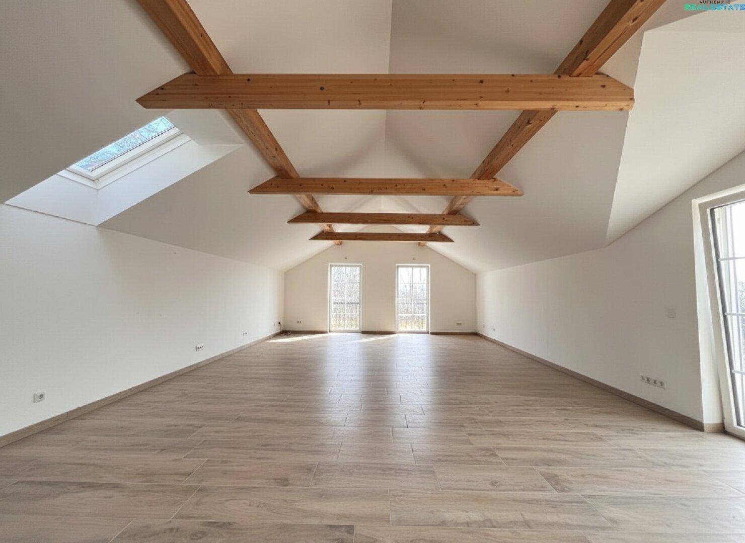 Ausgebauter Dachboden mit sichtbaren Holzbalken, Dachfenstern und viel Platz.