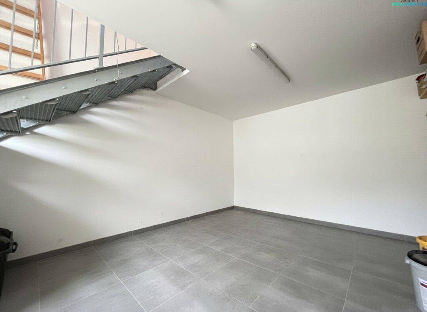 Kellerraum mit Fliesenboden und Metalltreppe, ideal als Abstellraum oder Werkstatt.