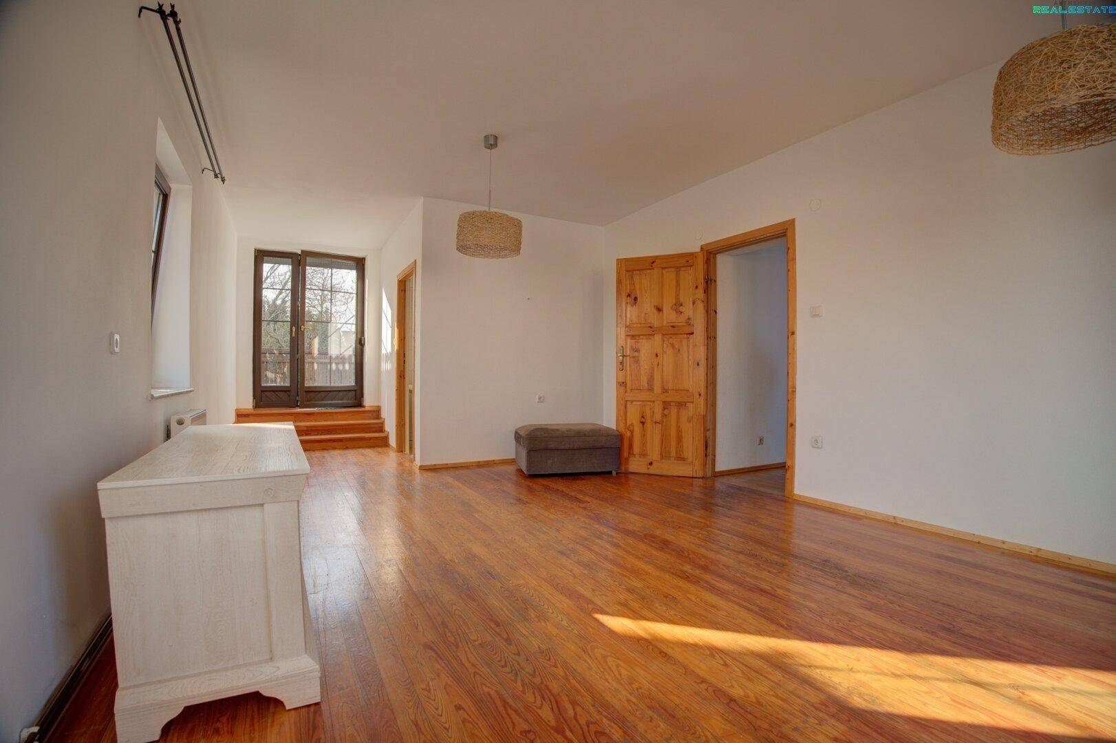 Geräumiges Zimmer mit Holzboden und Zugang zu einem Außenbereich.