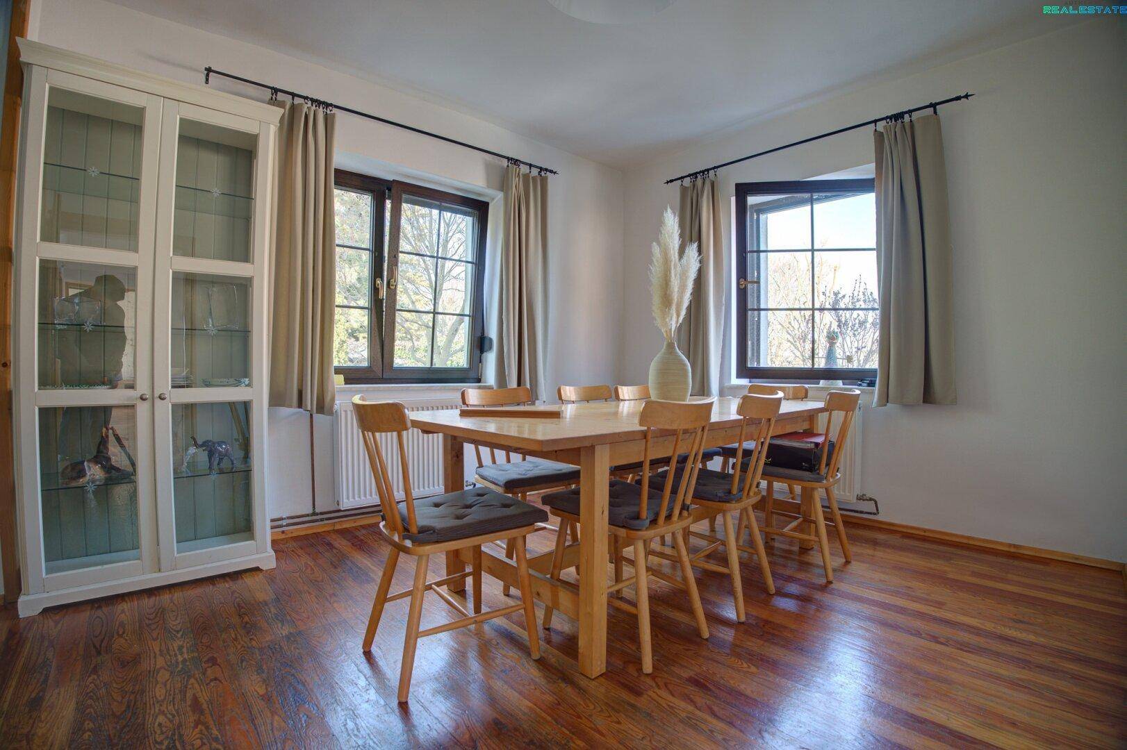 Helles Esszimmer mit Holztisch, Stühlen und Vitrinenschrank.