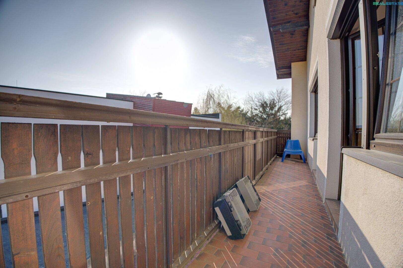 Schmaler Balkon mit Ziegelboden und Holzgeländer.