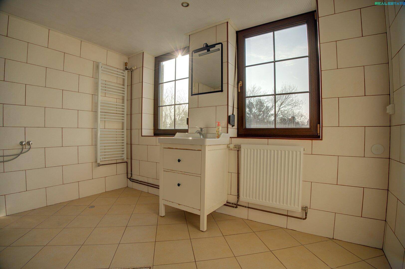 Badezimmer mit Waschbecken, Spiegel und Fliesenboden.
