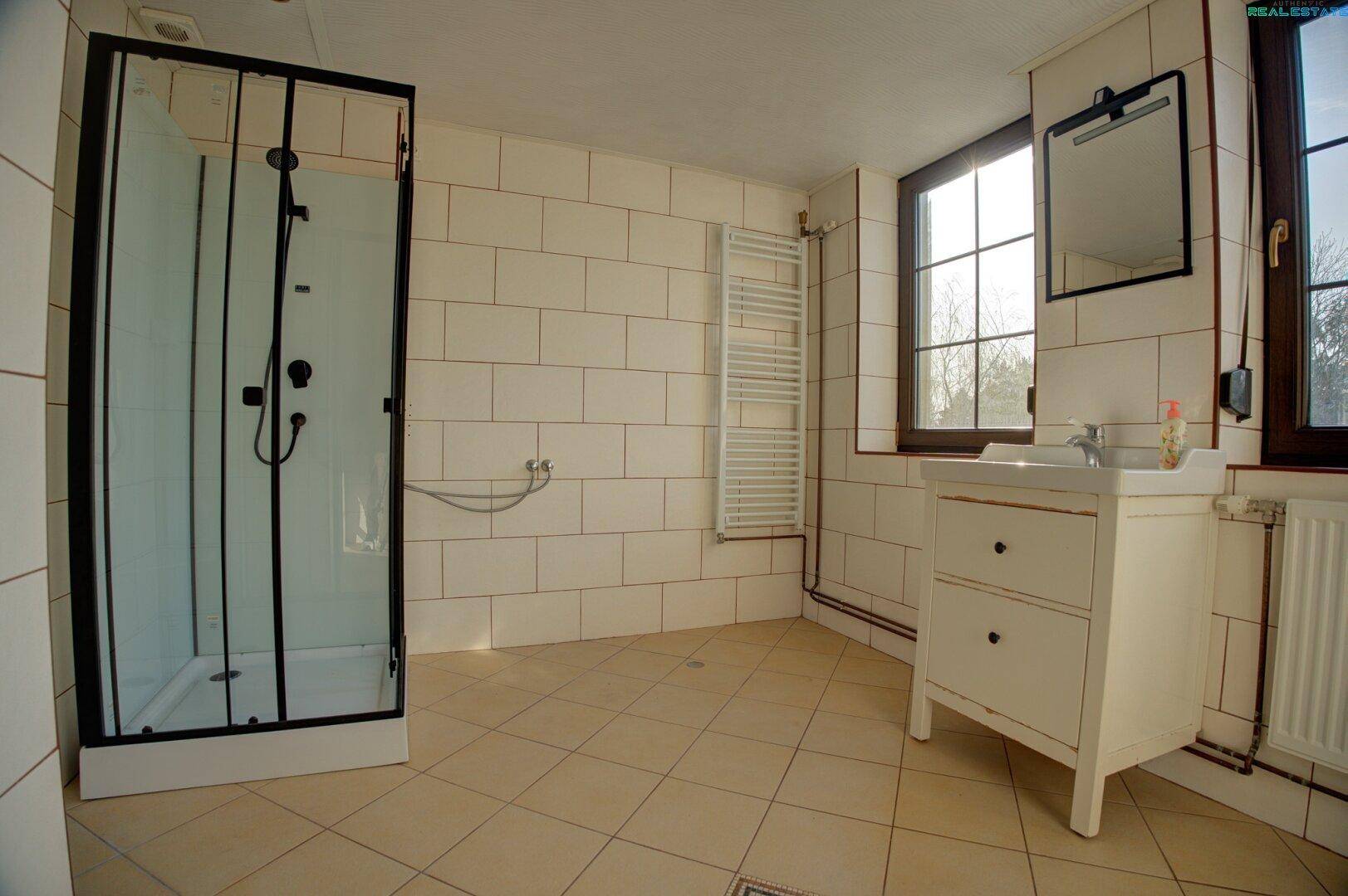 Badezimmer mit Duschkabine, Waschbecken und Fliesenboden.
