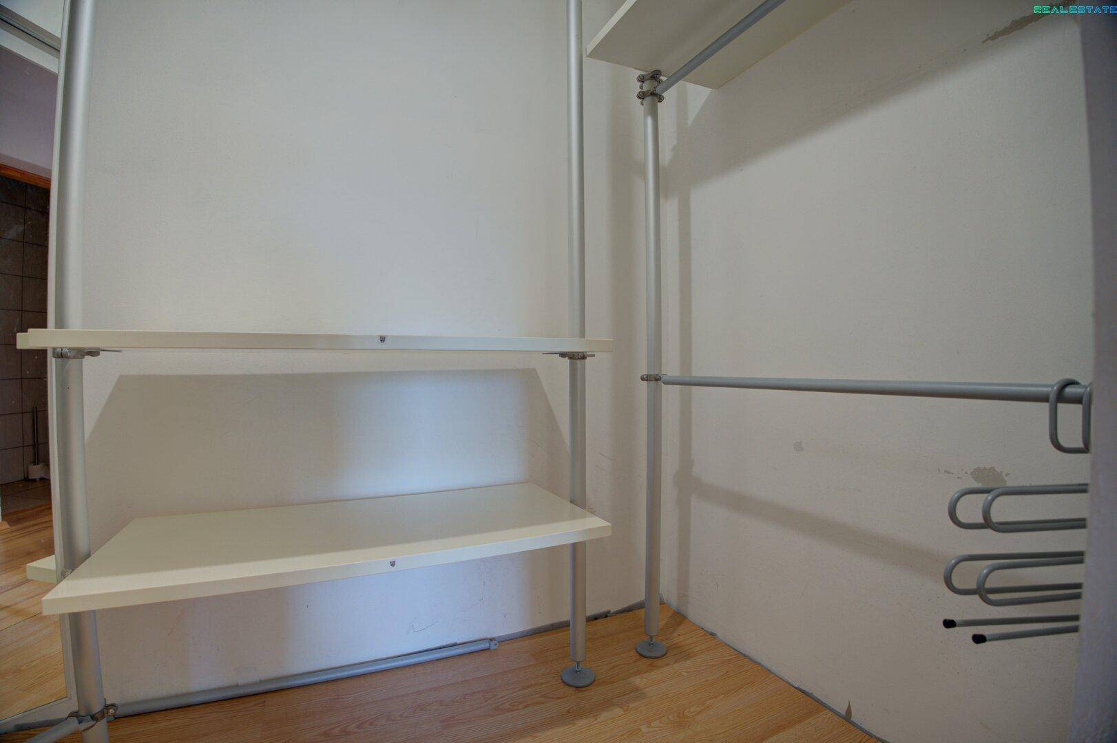 Begehbarer Kleiderschrank mit Regalsystem und Holzboden.