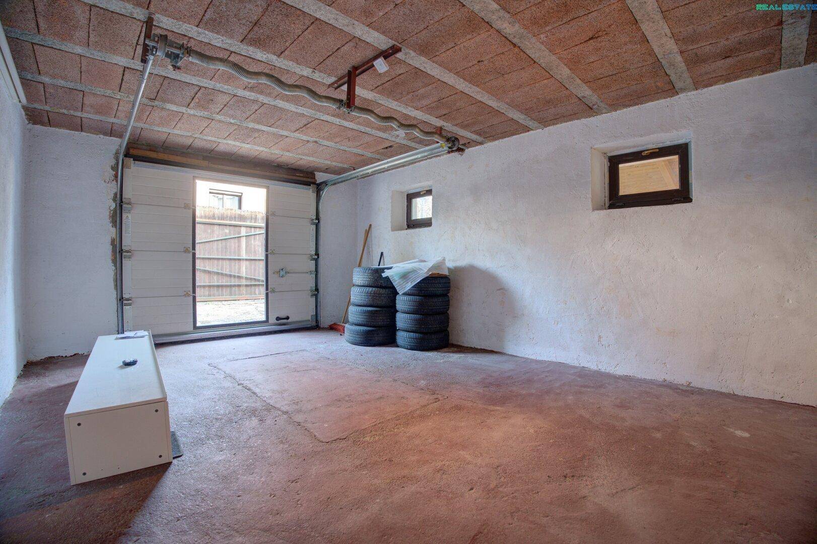 Geräumige Garage mit Garagentor und Stauraum für Reifen.