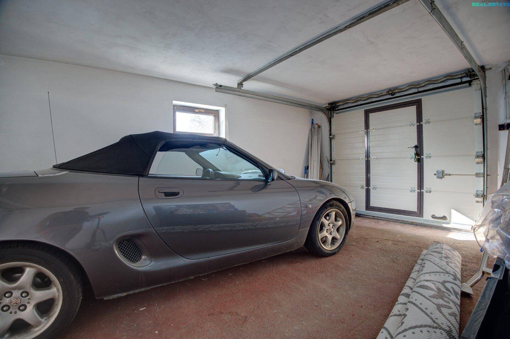Garage mit geparktem Auto und Garagentor.